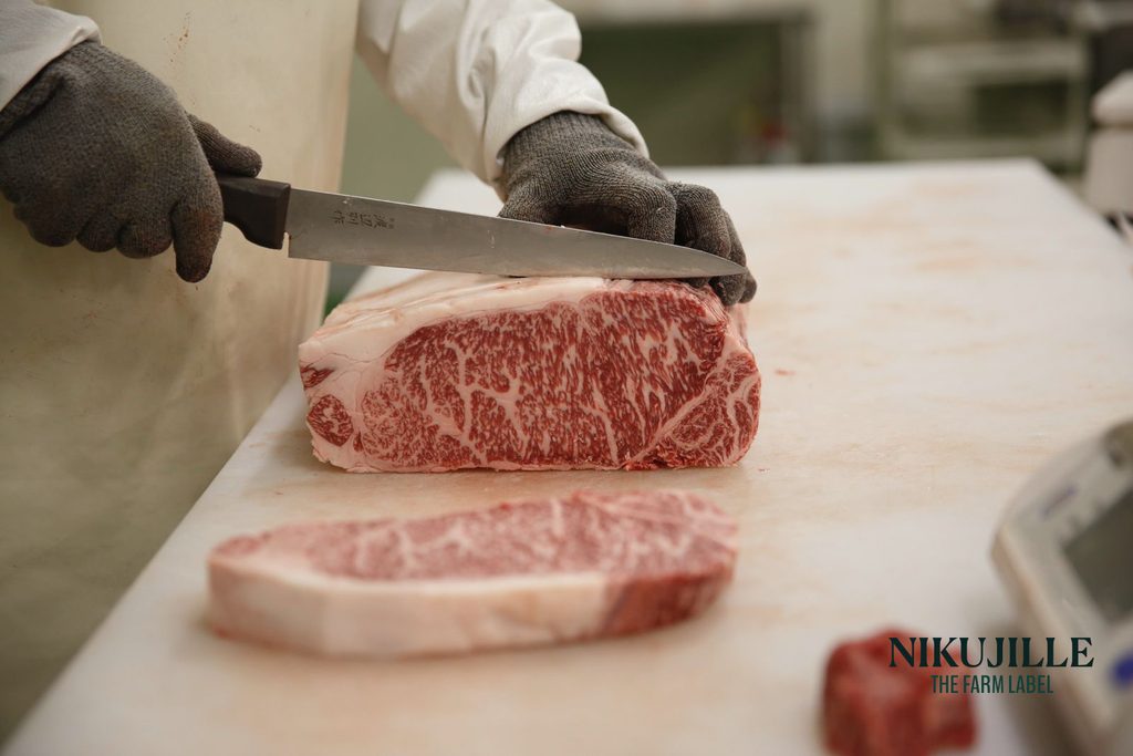 Chef slicing a wagyu ribeye block into steaks on a cutting board