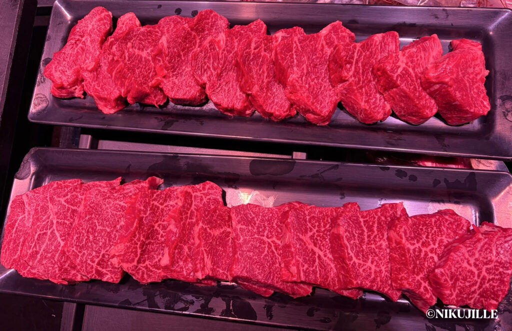 Two steel trays of fresh raw Japanese wagyu cuts with fine, even marbling and a deep red color.